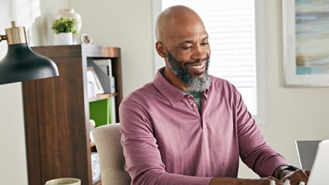 A retired man smiles while on his computer