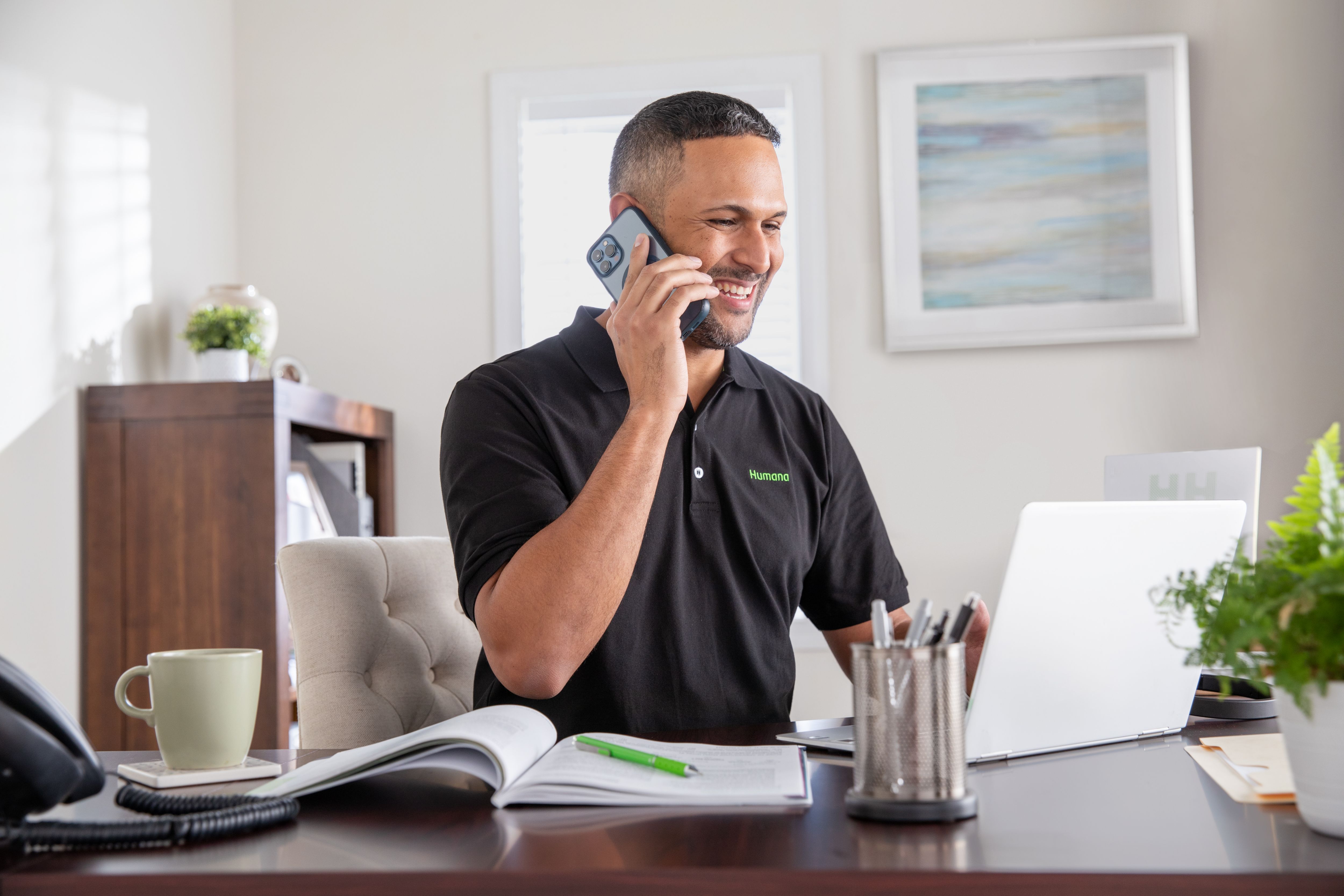 Humana agent working from home office talking on phone and looking at computer