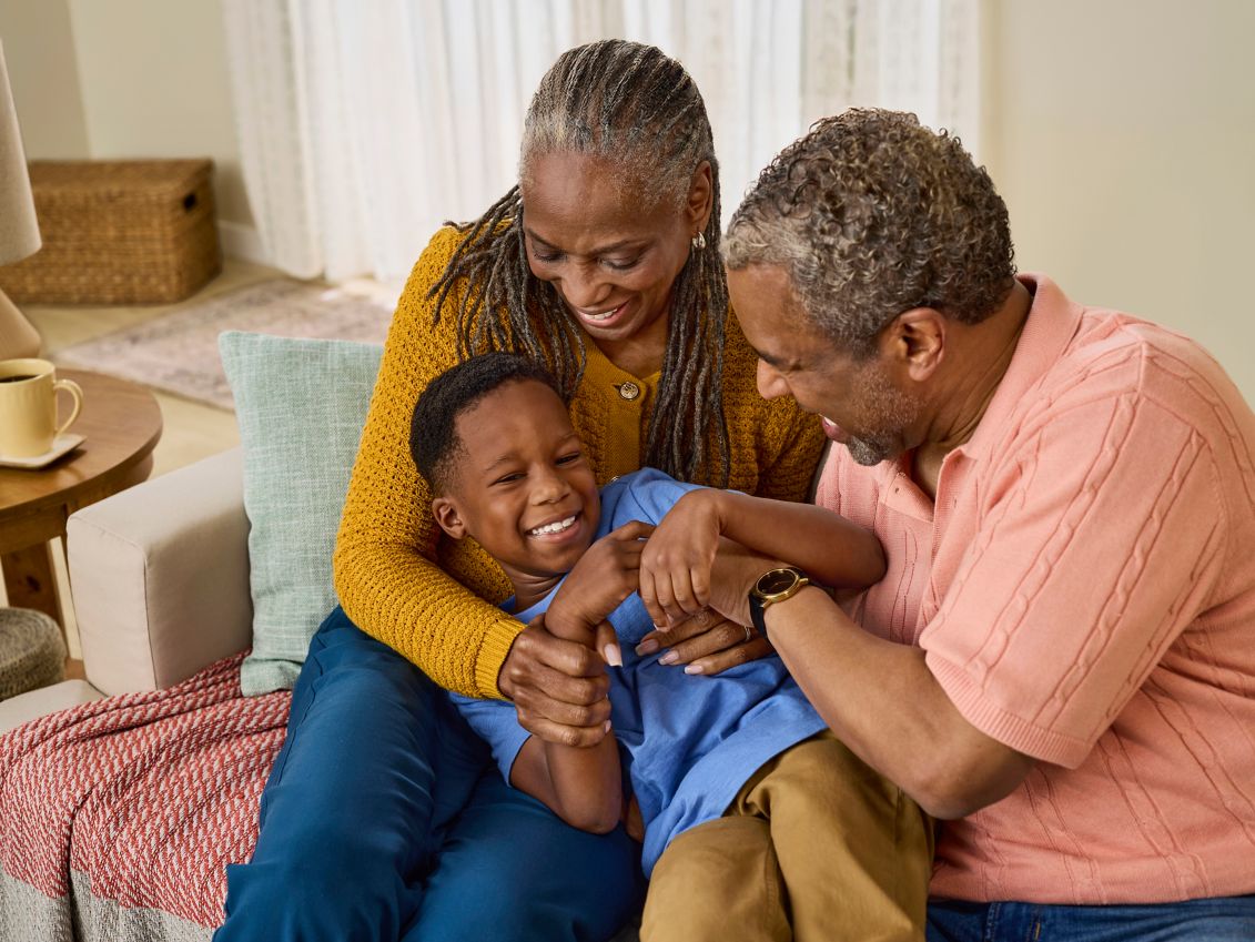 A couple laughs while playing with their grandson.   