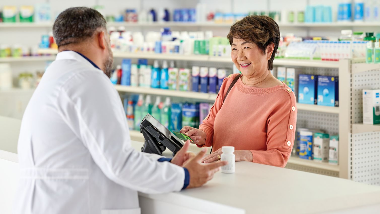 Woman talks to a pharmacist at counter.