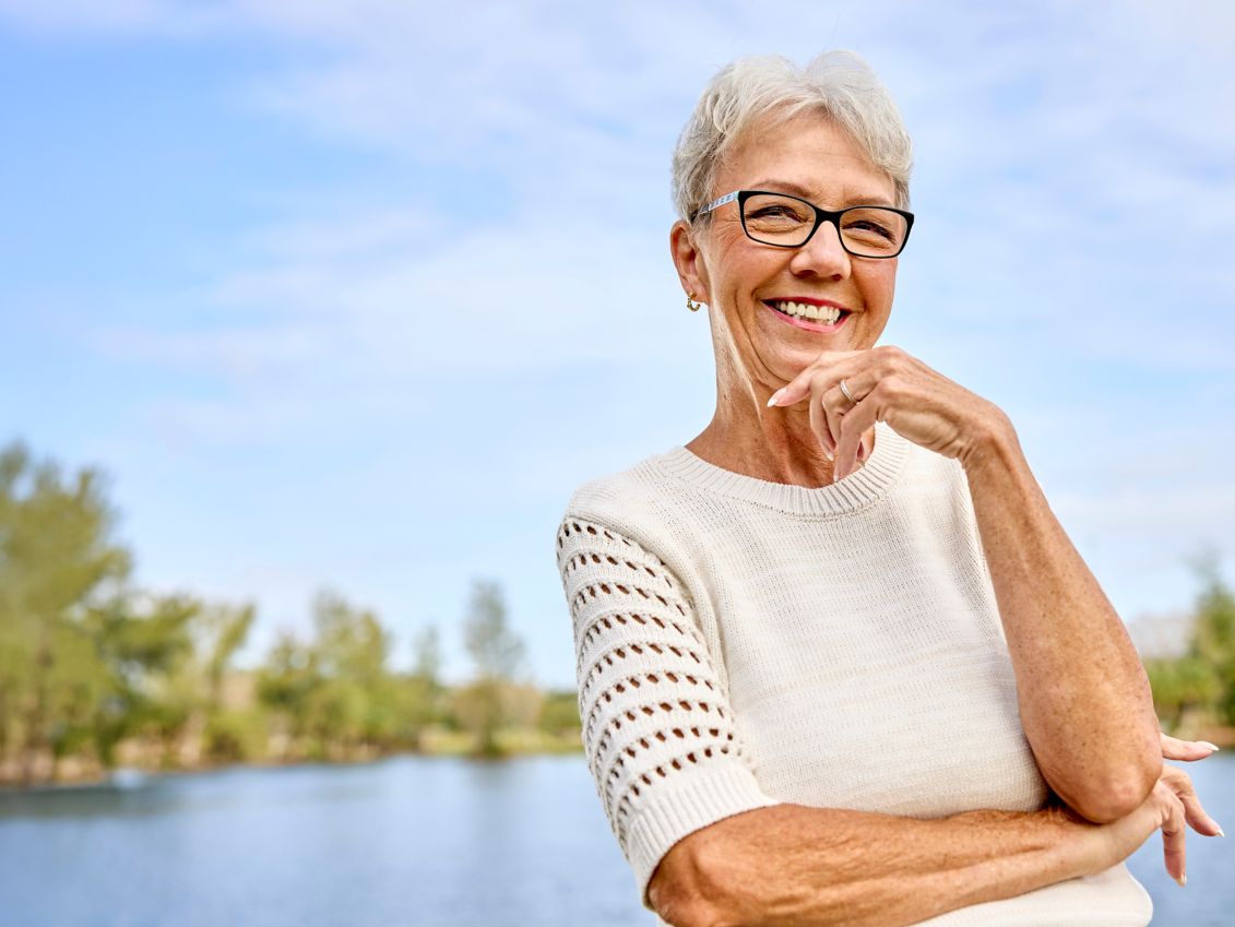 Woman smiling and standing in front of a lake.