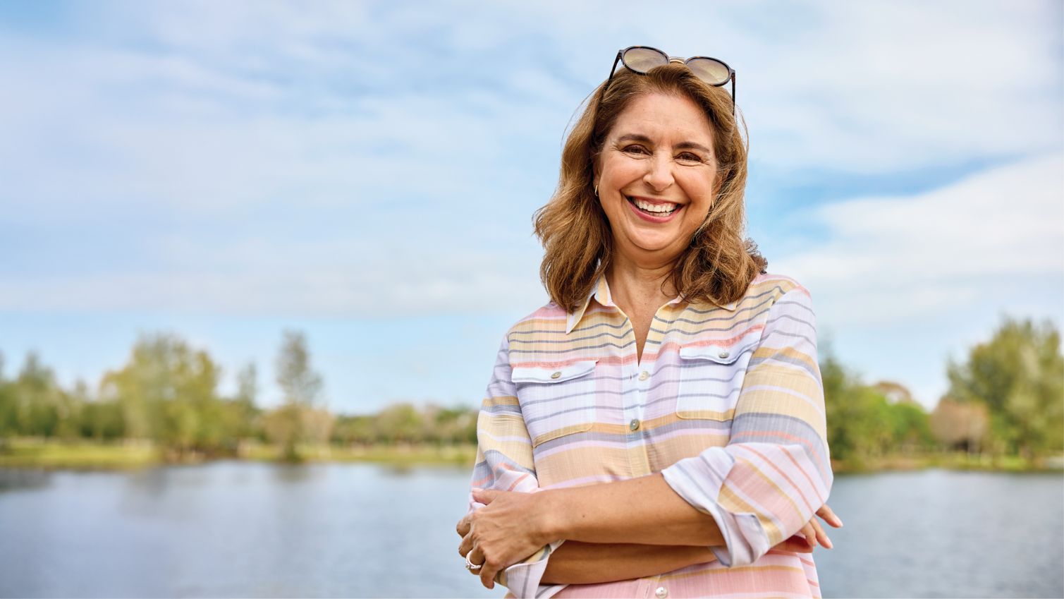 Woman smiling and standing in front of a lake.