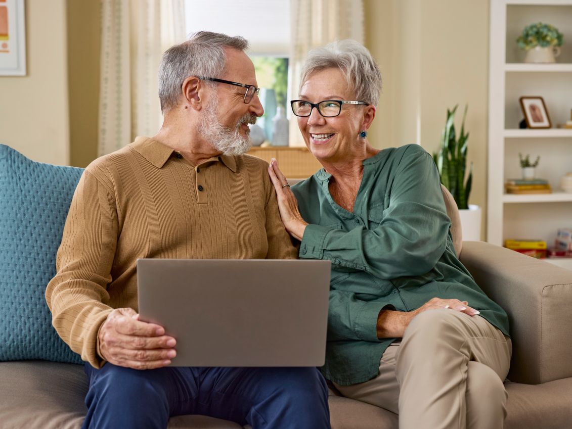 Man and woman using a laptop on a couch.