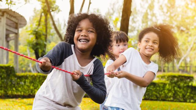 Happy children playing tug of war.