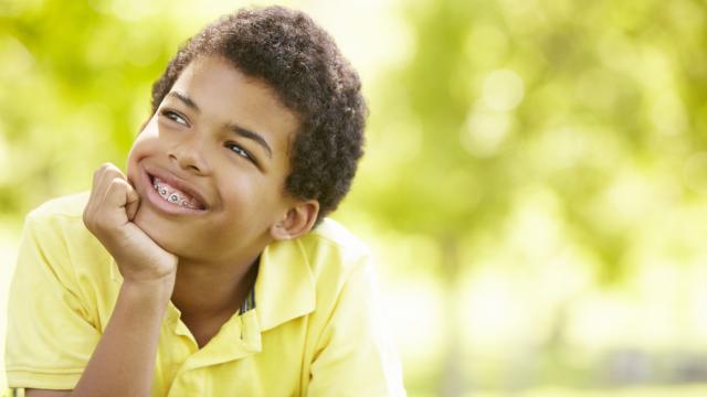 A boy with braces relaxes at a park. 