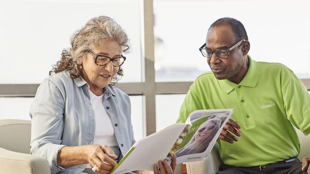 2 seniors read through a brochure about Humana insurance plans.
