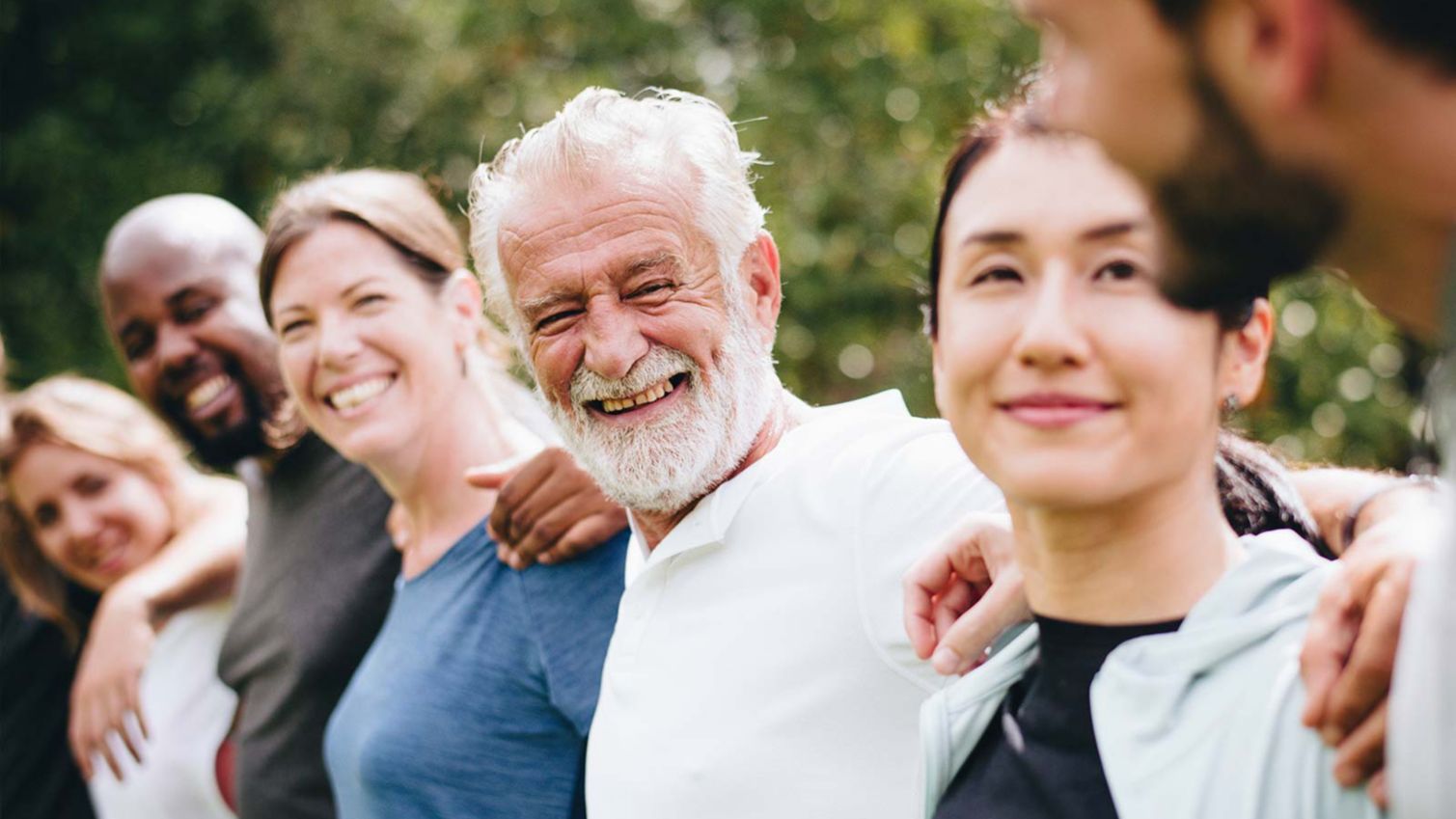 A group of people, arm in arm, smiling at the camera