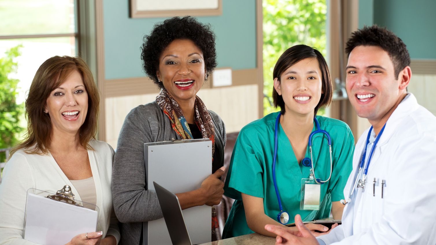 Four case and care management providers smiling at a desk