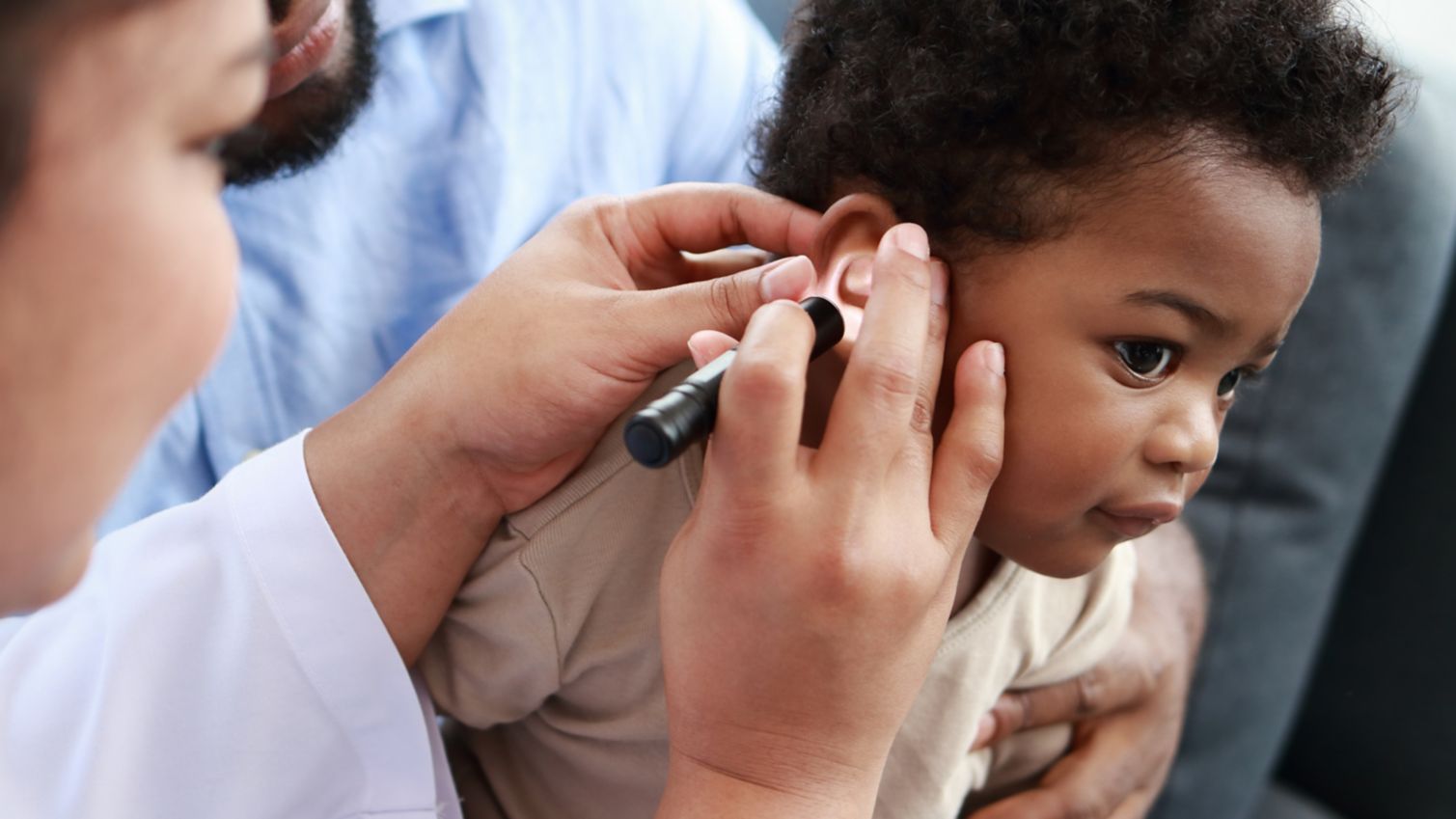Medicaid doctor examines a young baby's ear