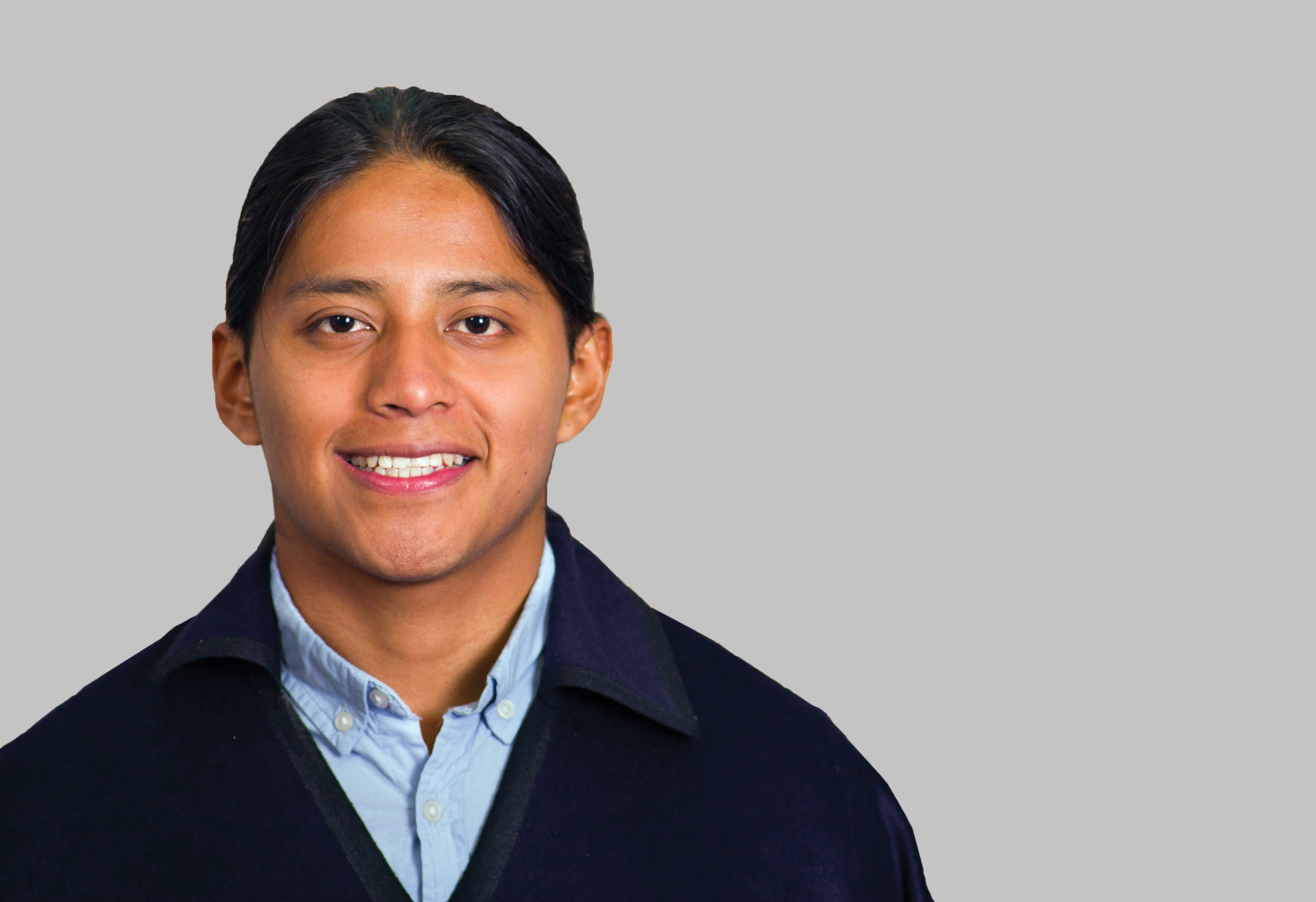 A younger Hispanic man wearing a blue shirt and jacket