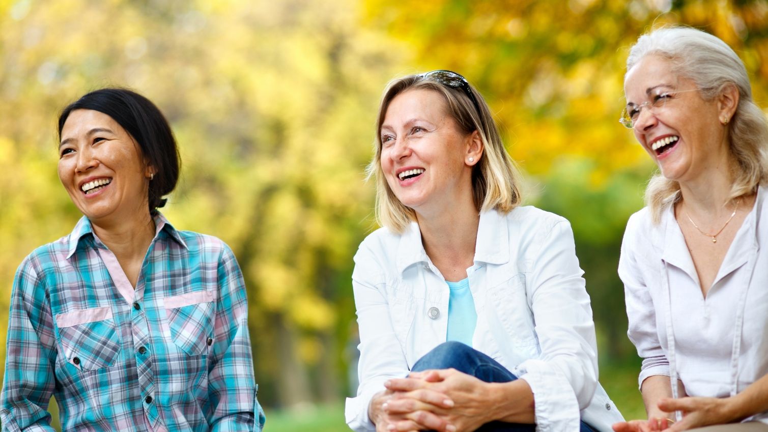 Three women are laughing in the garden.