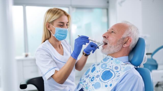 A dentist checks a man's teeth.