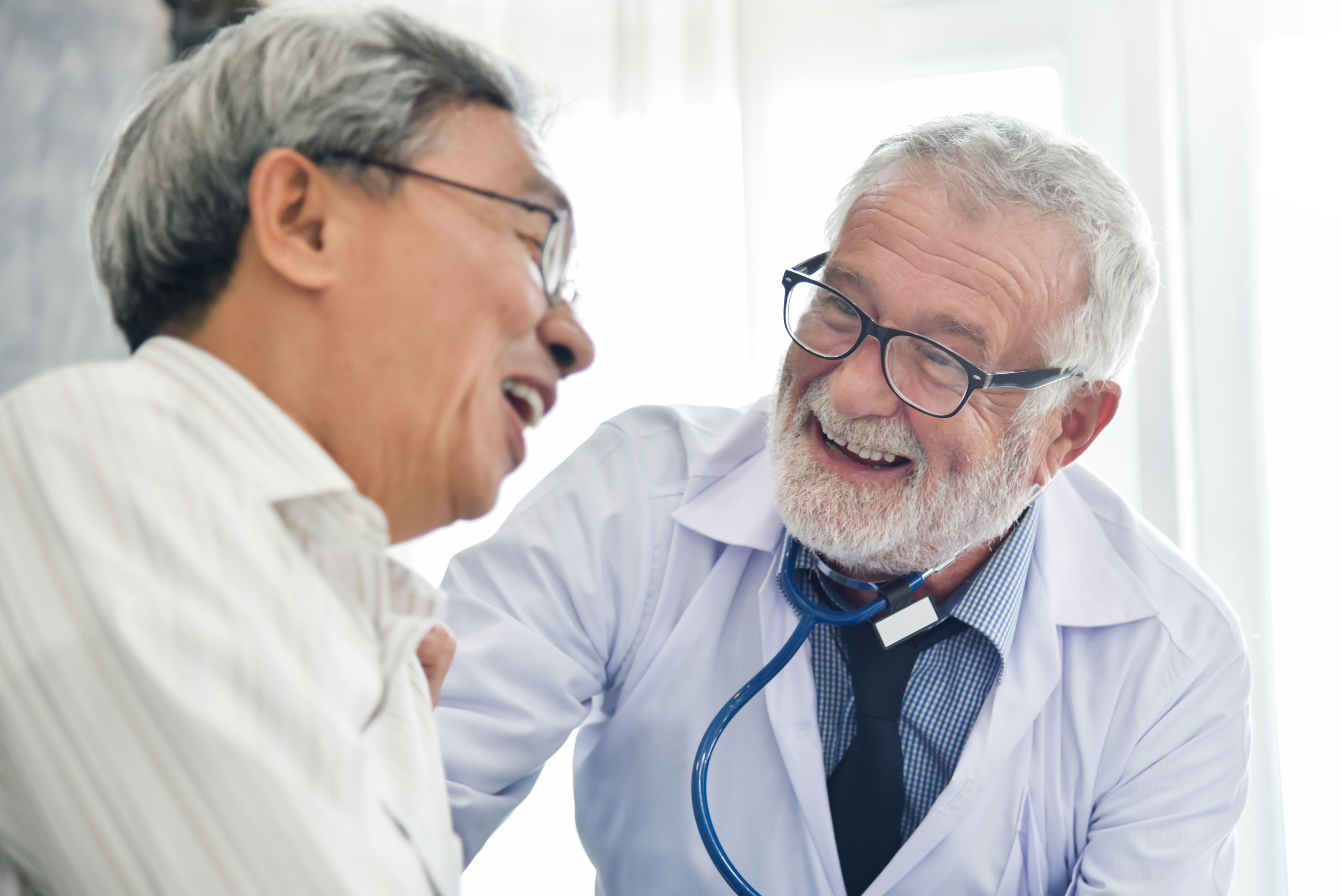 Happiness People.  Senior male Doctor and Asian male patient are talking in the medical room together. Smiling.