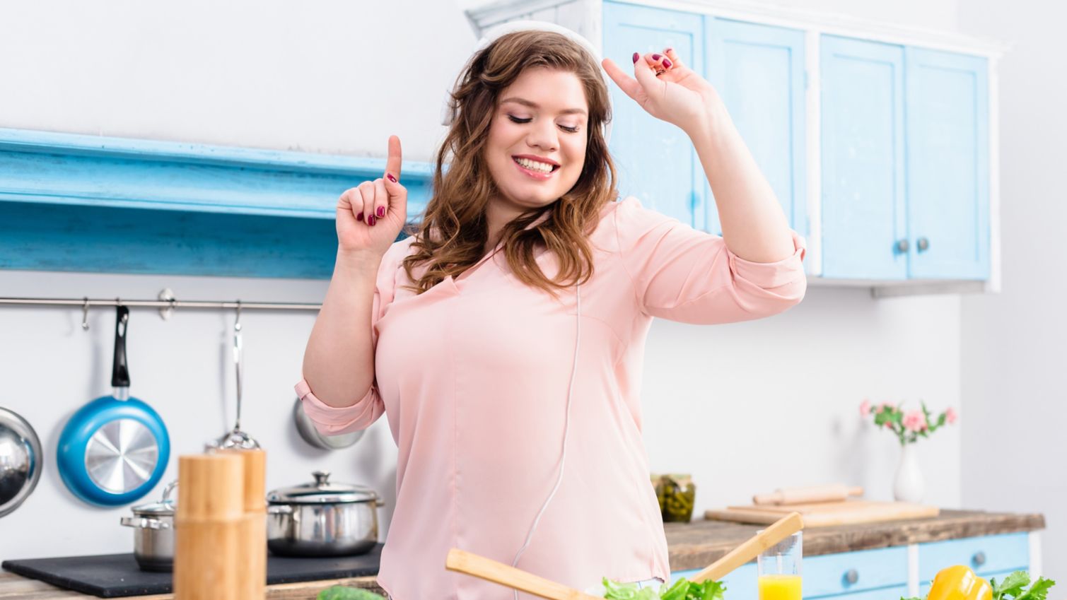 Woman happily dances while cooking a healthy meal.