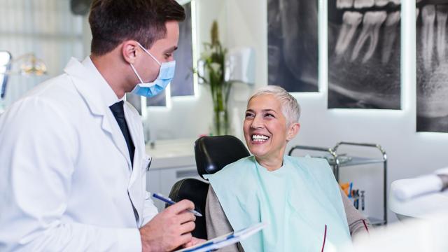 A woman smiles at her dentist while they discuss her care.