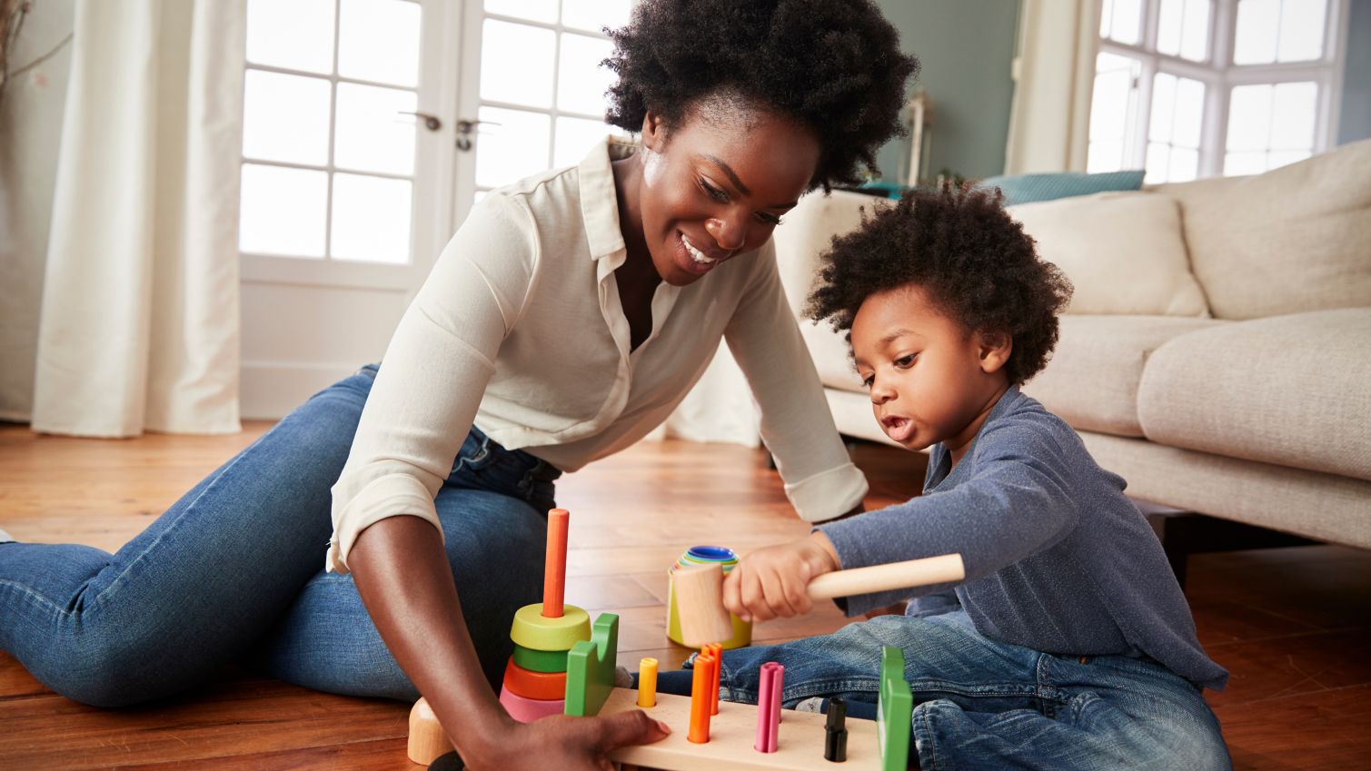 A mother plays with her son while sitting on the floor.