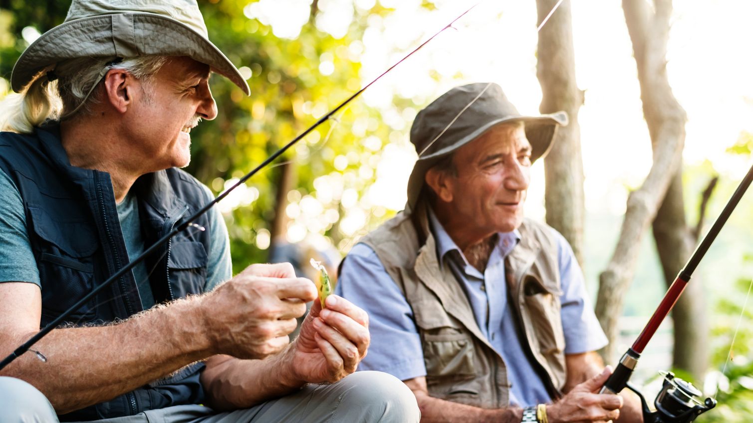 Two friends smile and fish together. 