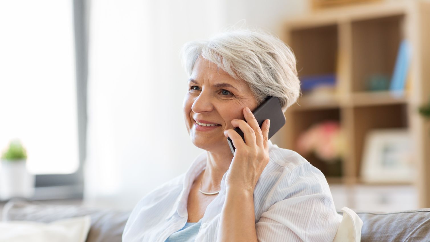 A woman smiles while on her phone at home. 