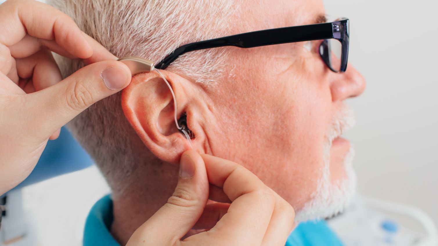 Senior man putting in hearing aids.