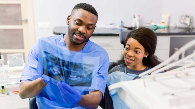 A dentist and patient look at X-rays together.