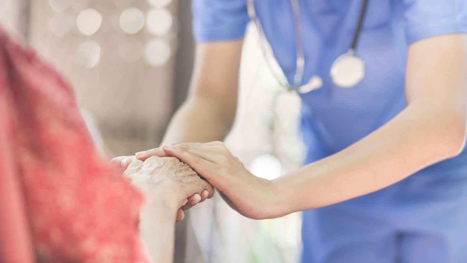 Medical worker holding hands with older woman.