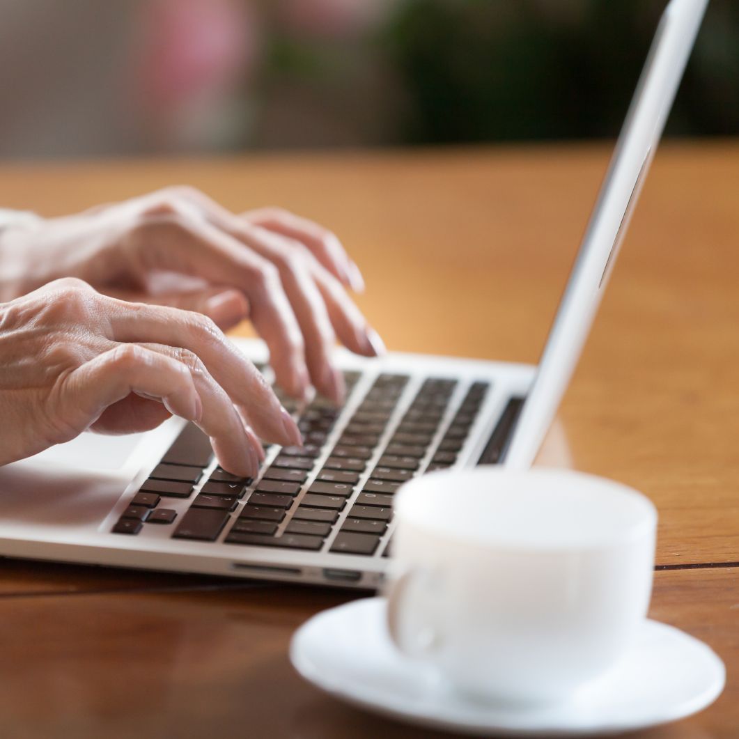 A woman's fingers type on a laptop.