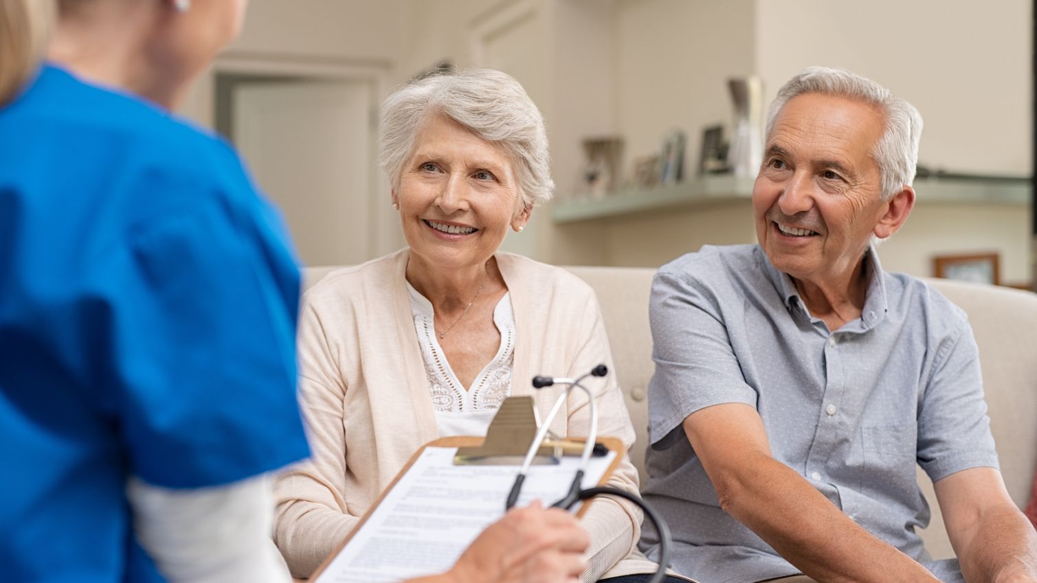 A couple speaks with a nurse during a home visit. 