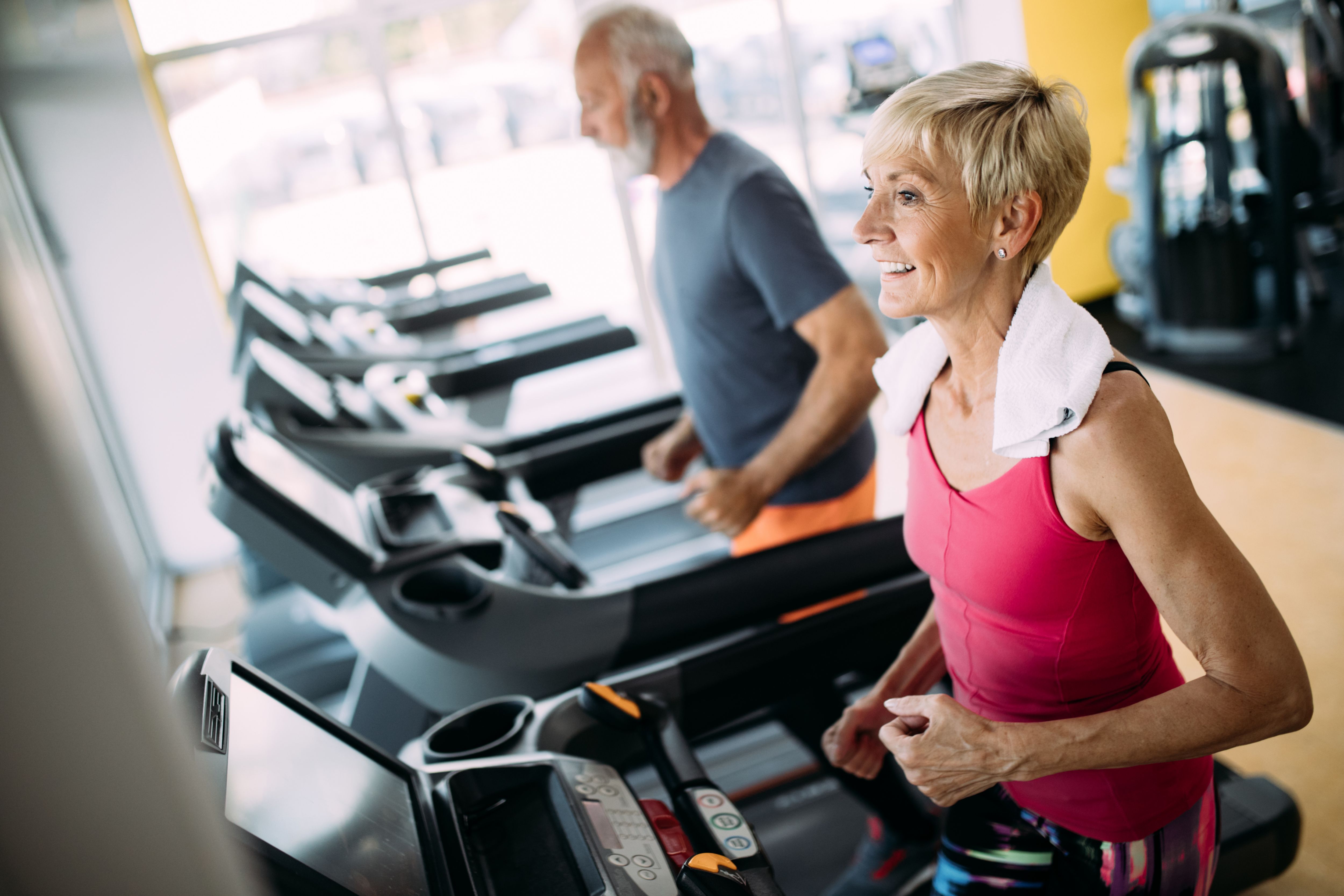 Mature people running in machine treadmill at fitness gym club