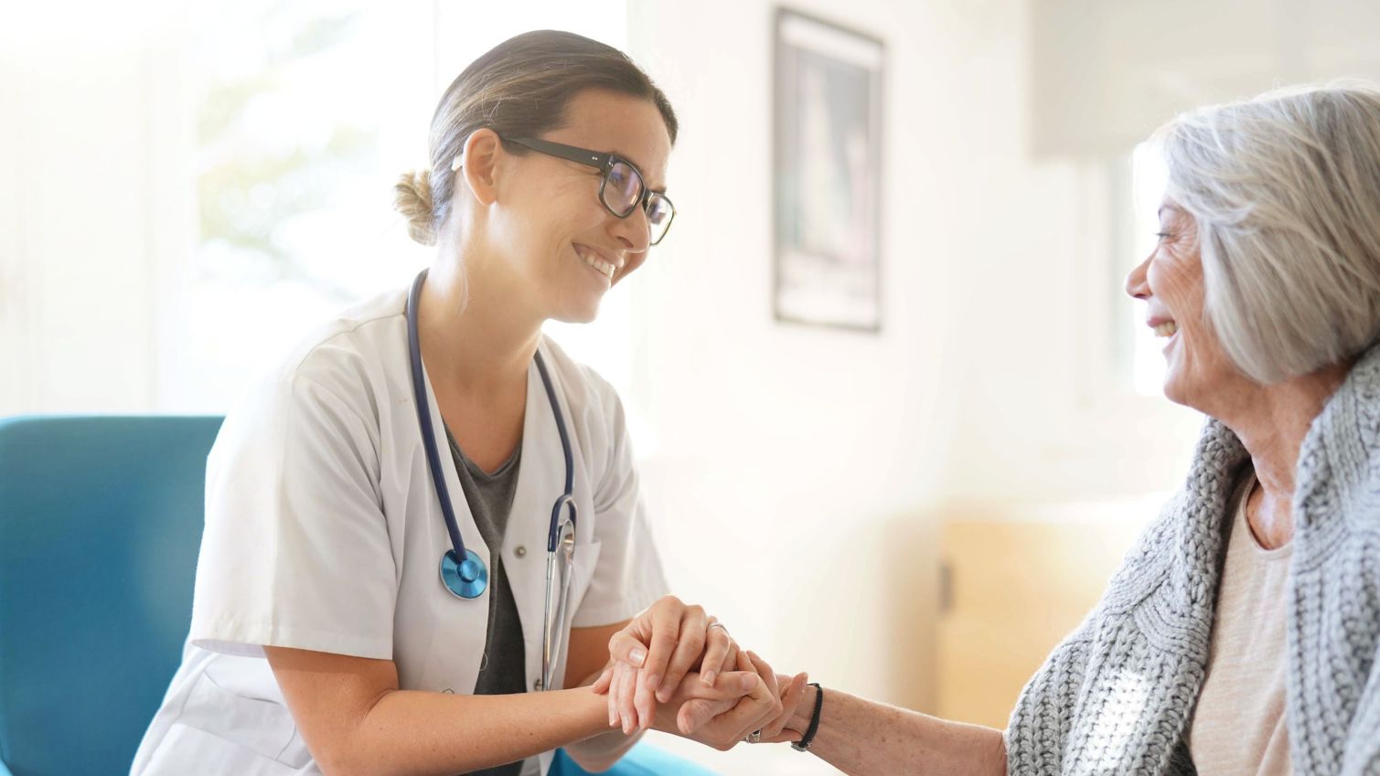 Young woman doctor speaks with older woman patient.