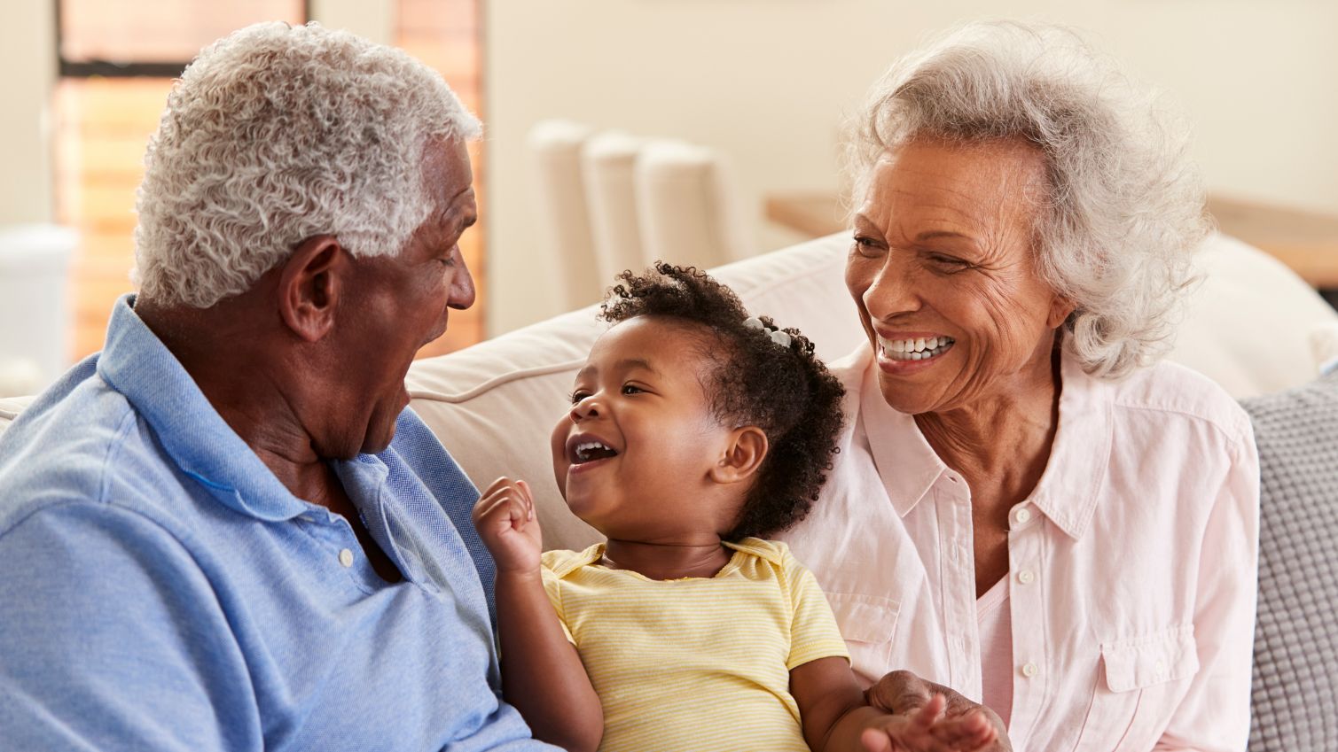 Grandparents play with granddaughter on couch