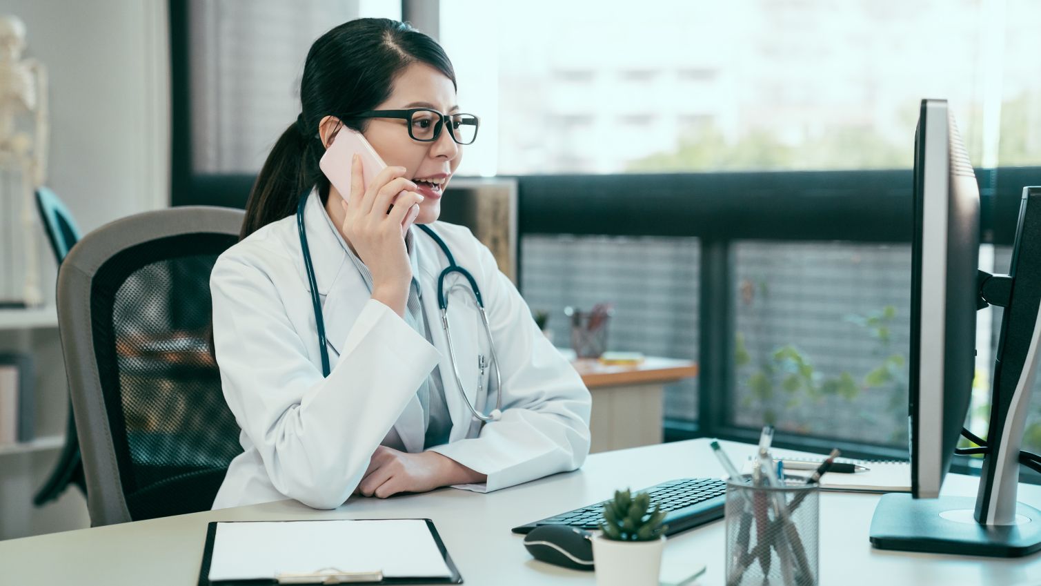 Healthcare professional on phone and looking at laptop