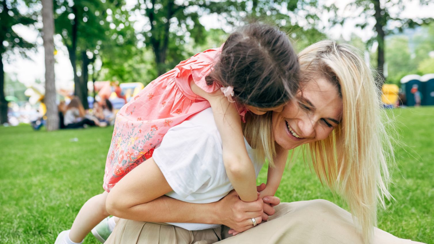 Mother looking at son and holding him up in air while both laugh.