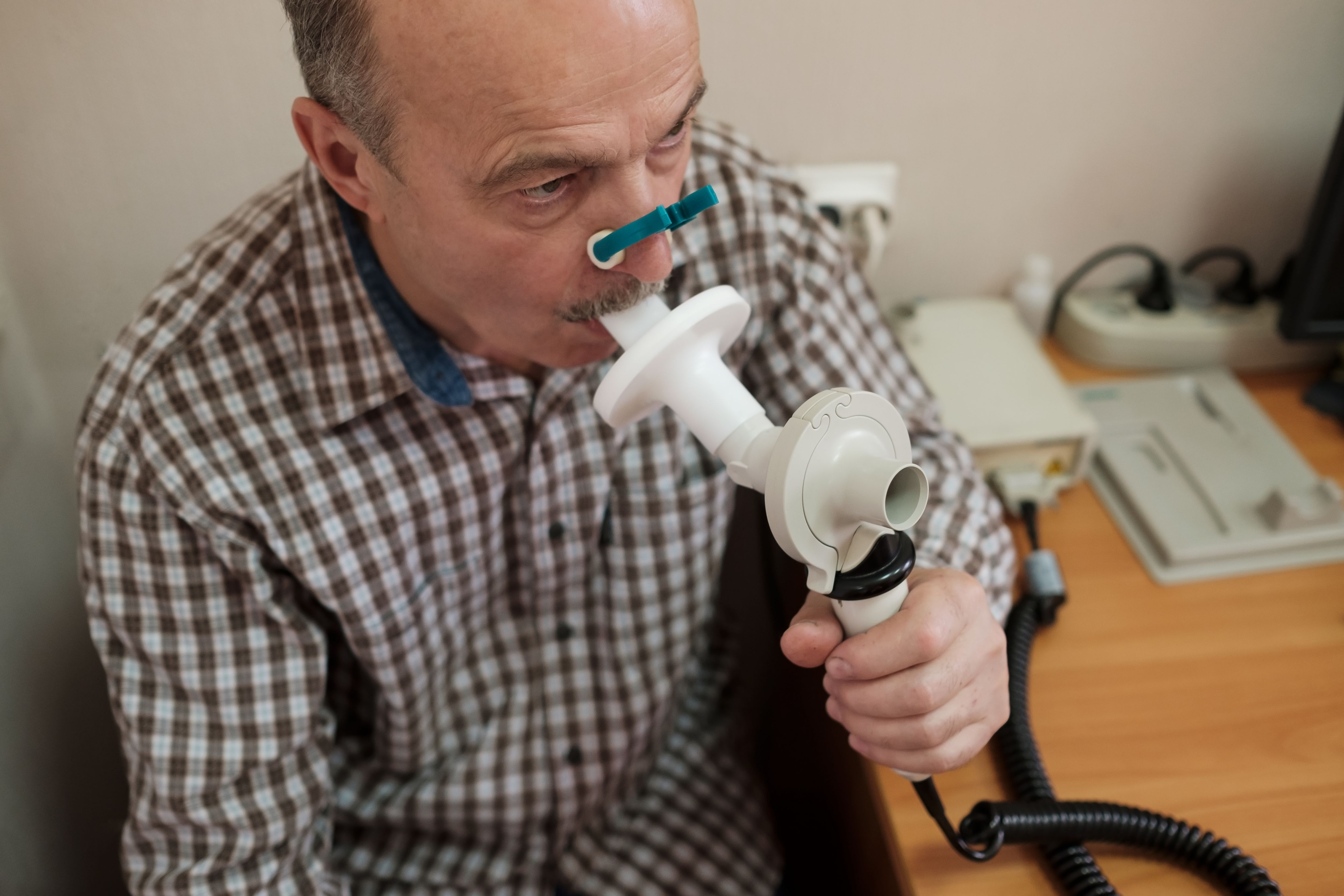 Senior hispanic man man testing breathing function by spirometry. Diagnosis of respiratory function in pulmonary disease