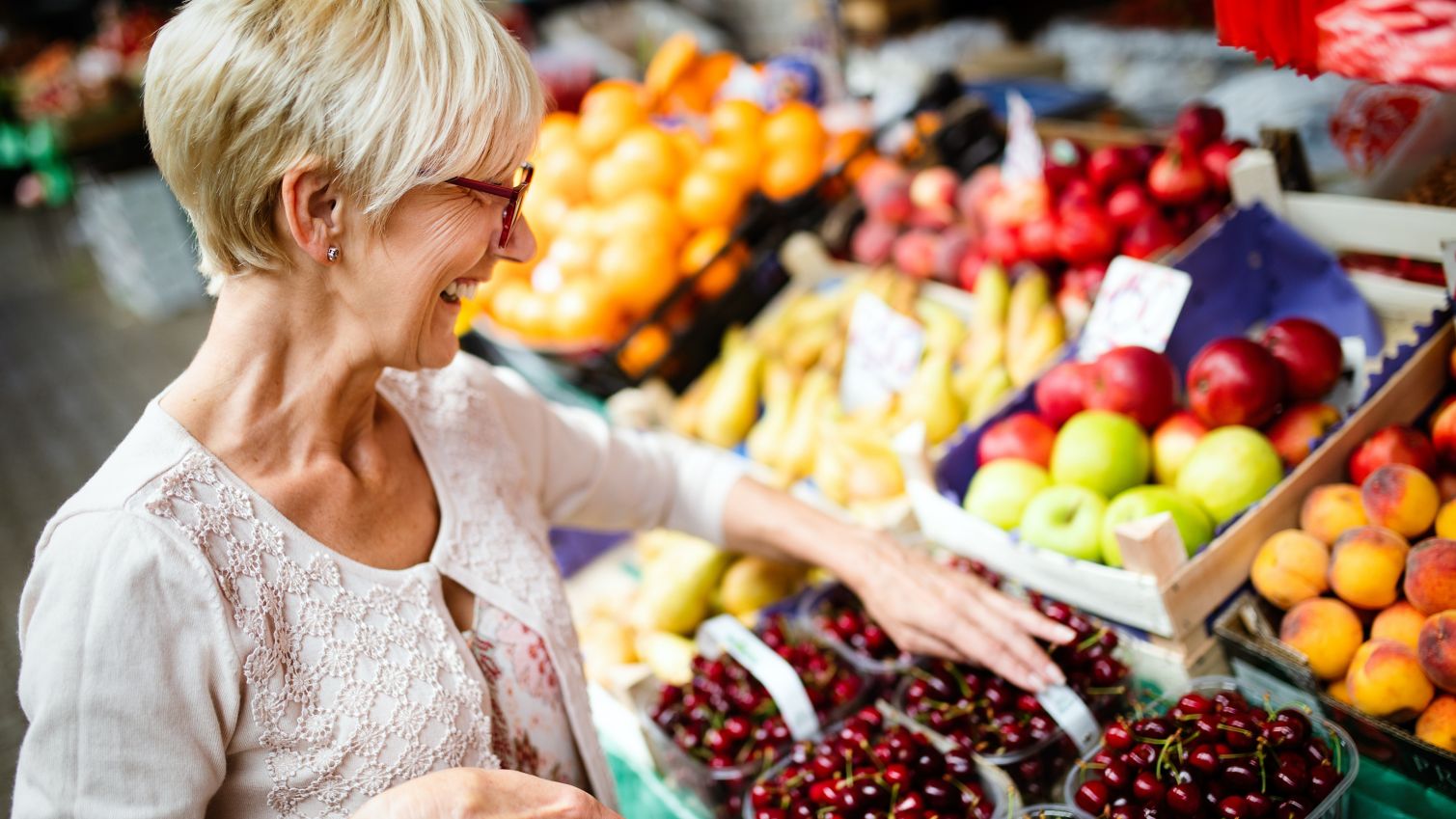 Older woman shops for fresh fruit in grocery store.