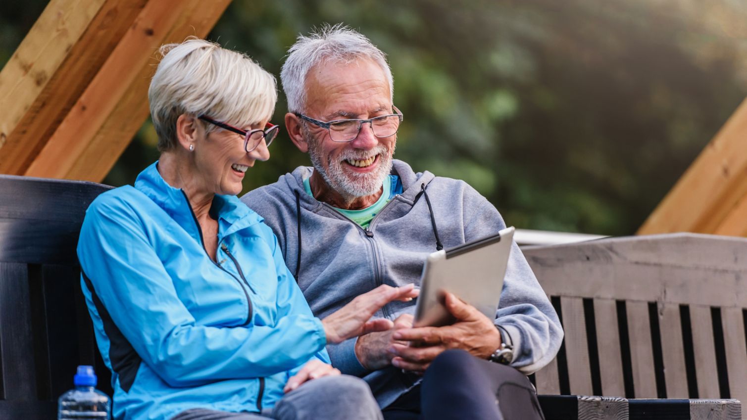 Smiling man and woman use a tablet.