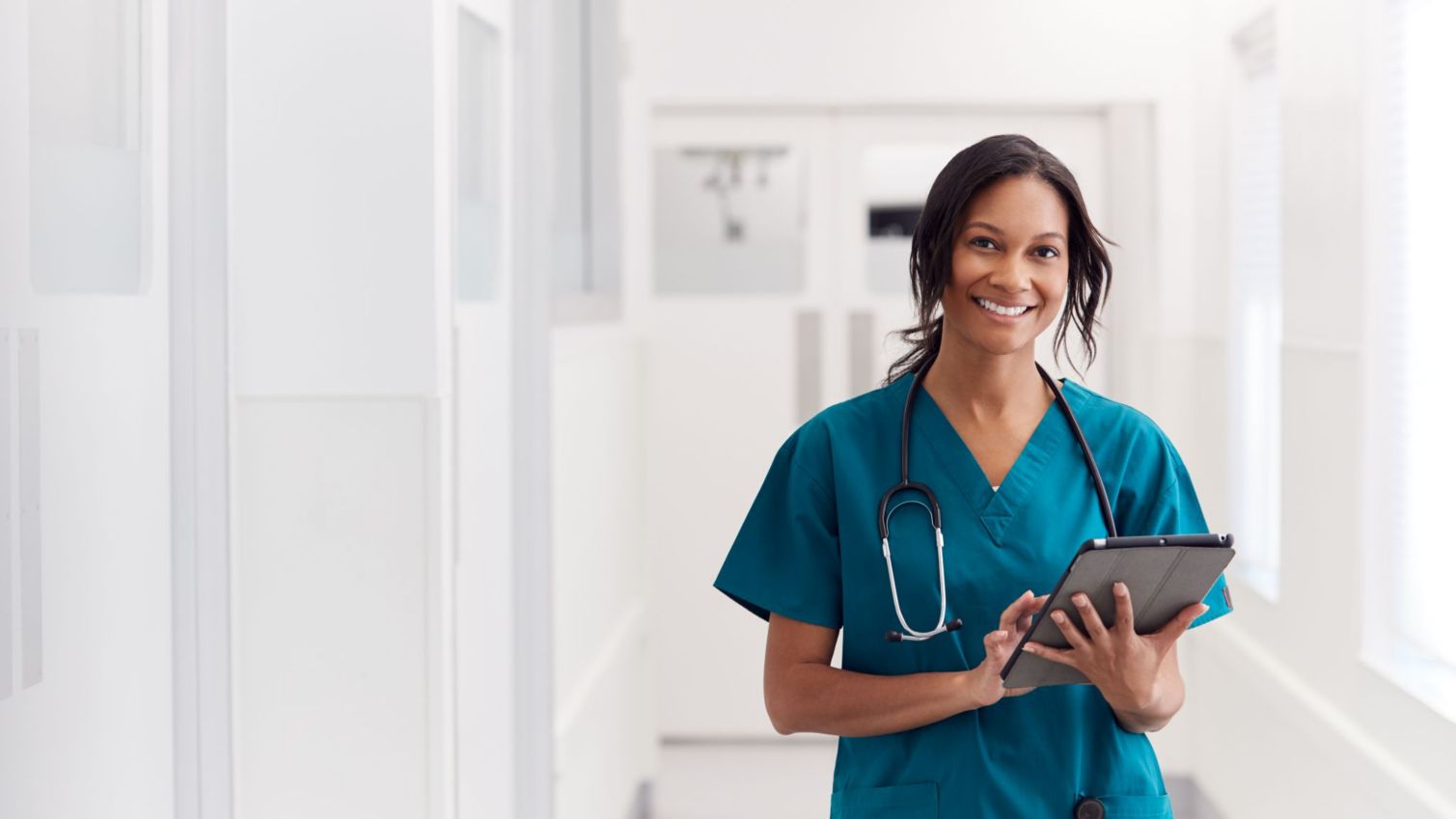 A smiling physician holds a tablet