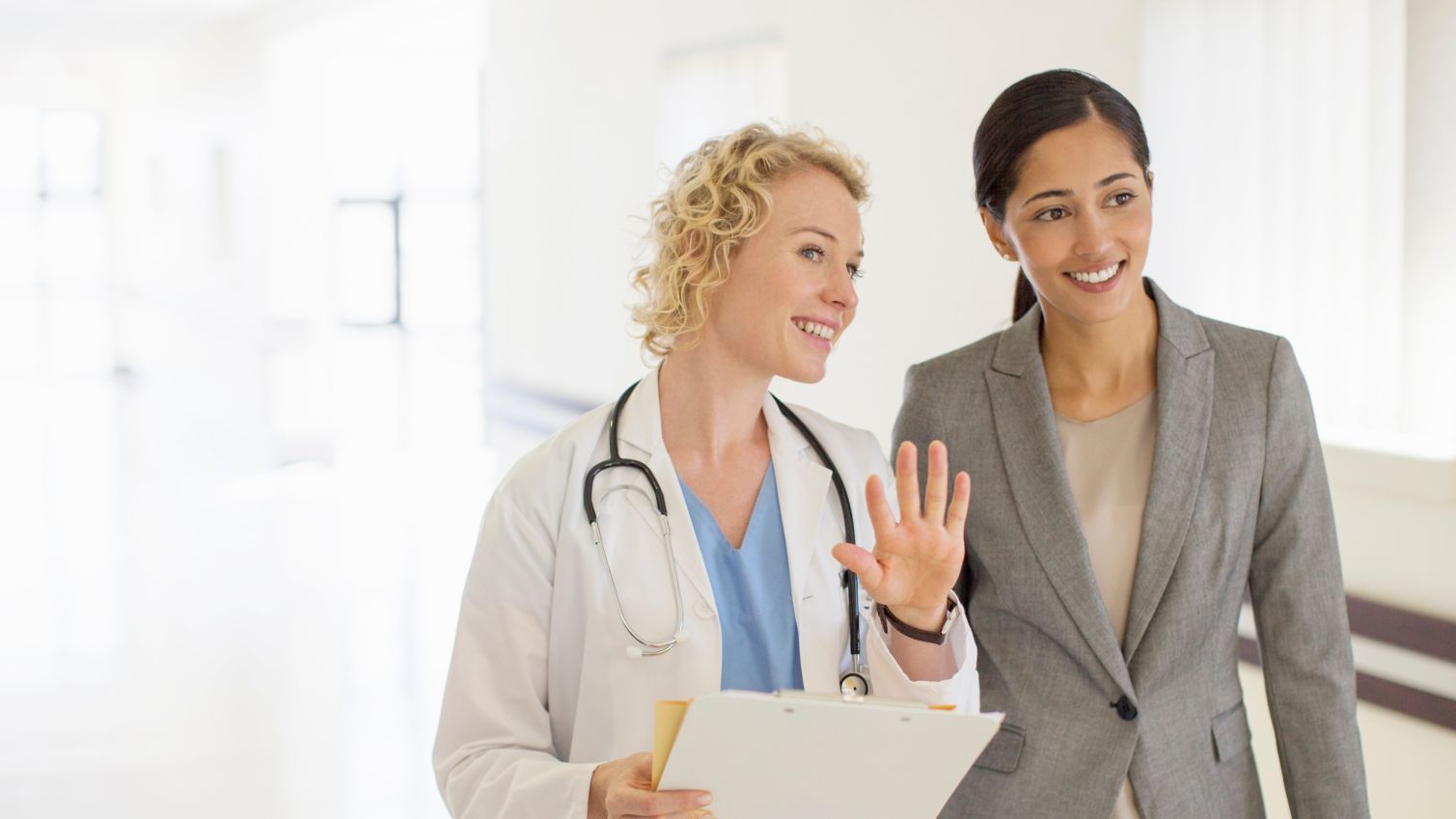 Doctor and businesswoman talking in hospital corridor