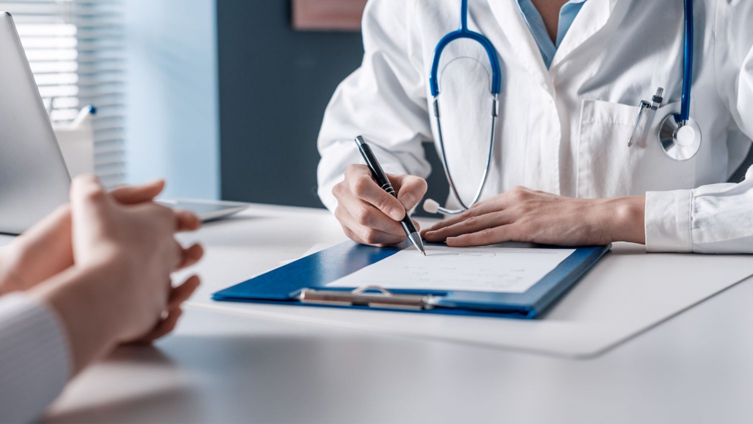 Healthcare professional writing in chart
