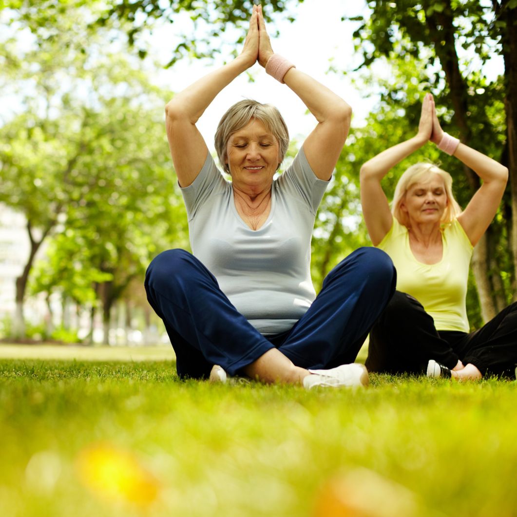 Two women practice yoga outdoors.