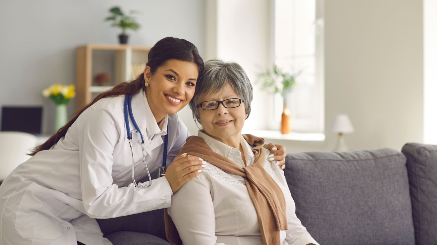 A medical provider and patient in an office setting smile at the camera. 