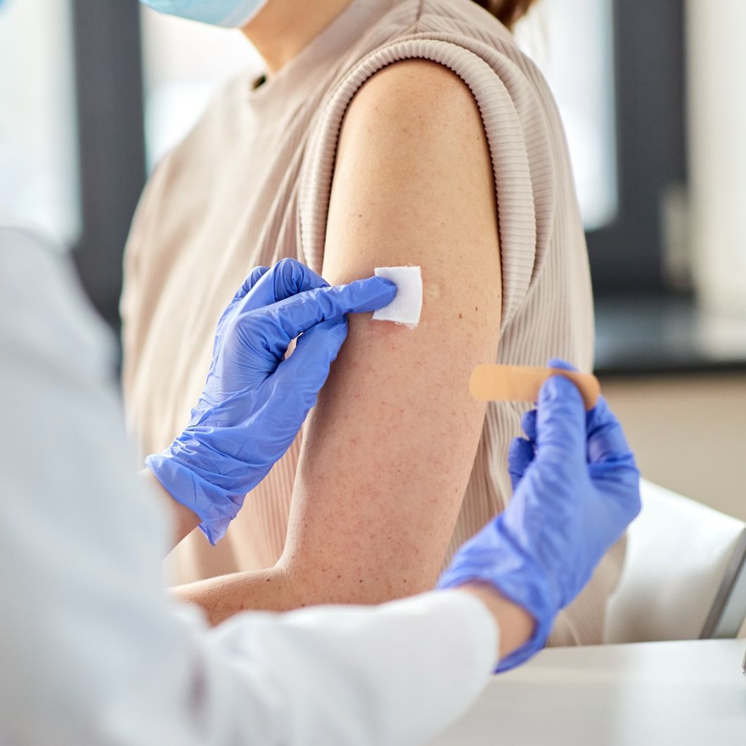A healthcare professional puts a bandage on a patient’s arm.