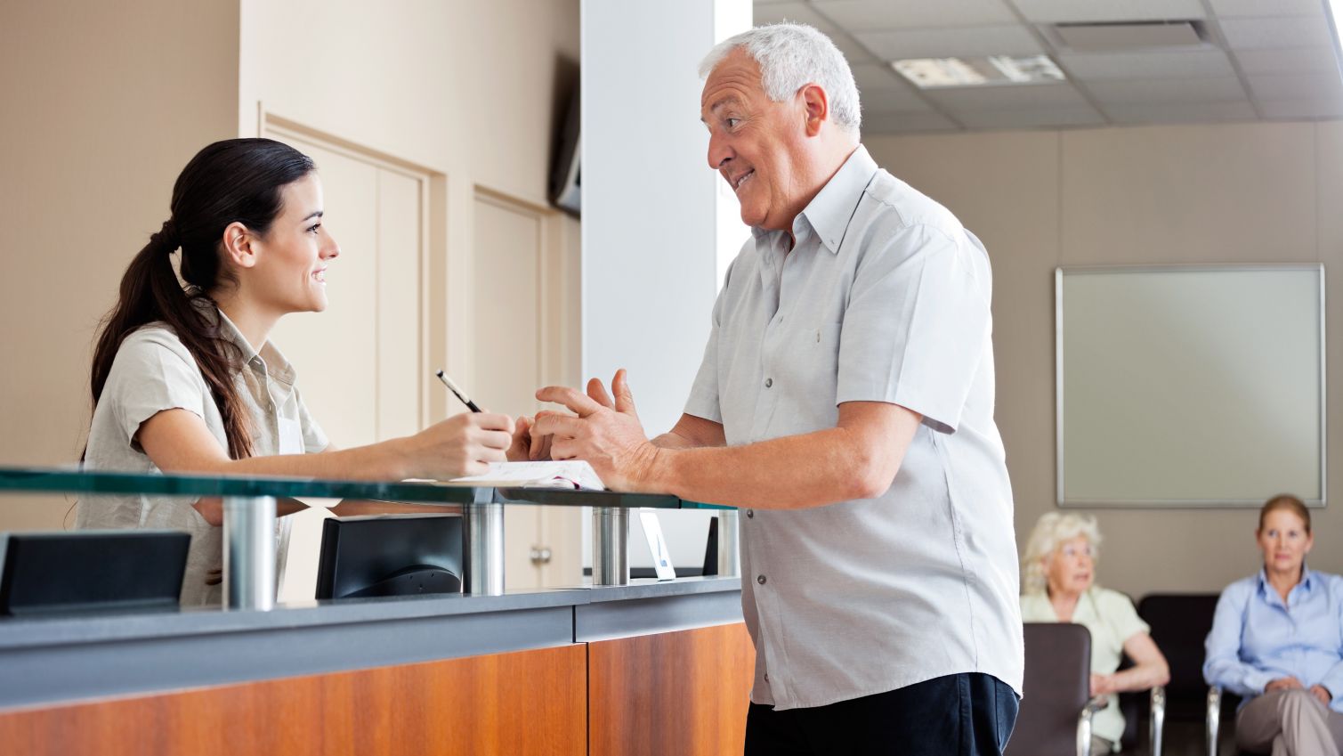 Woman hospital receptionist speaks to a male patient.
