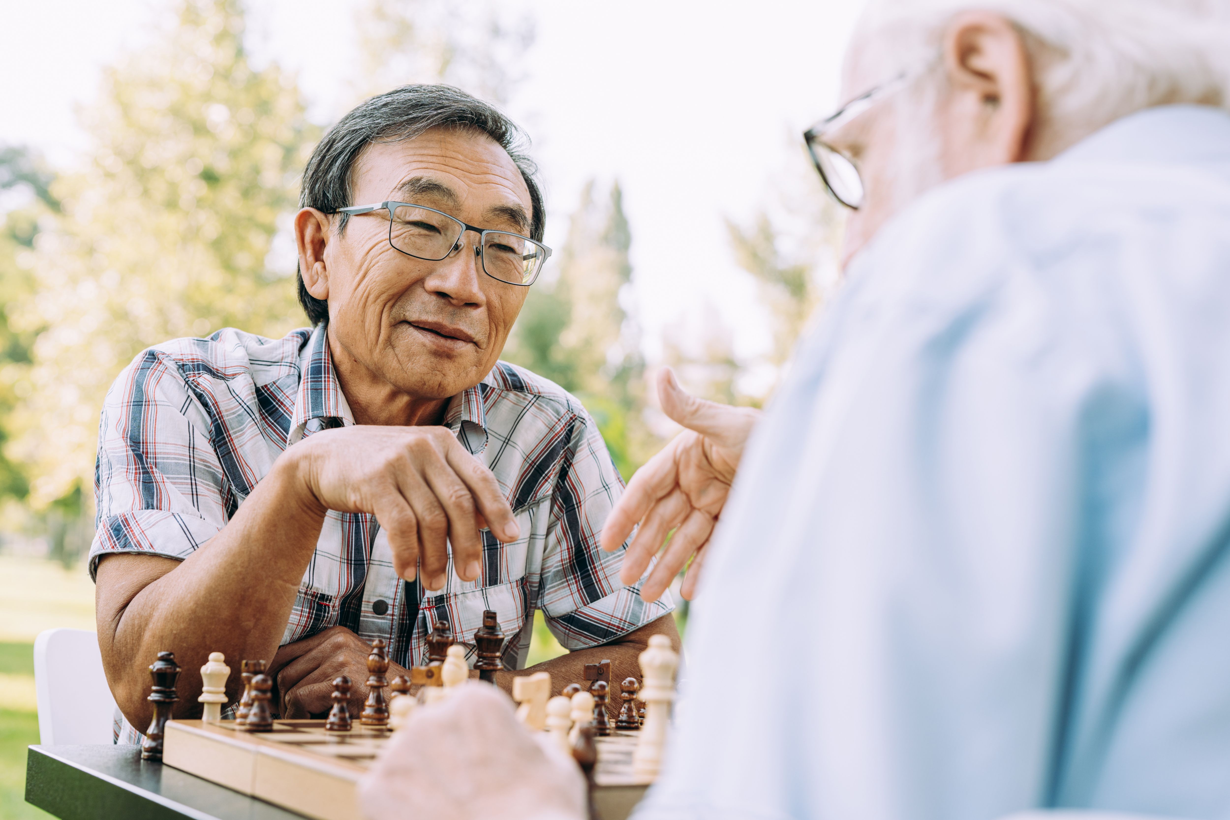 Two senior men playing chess outdoors.