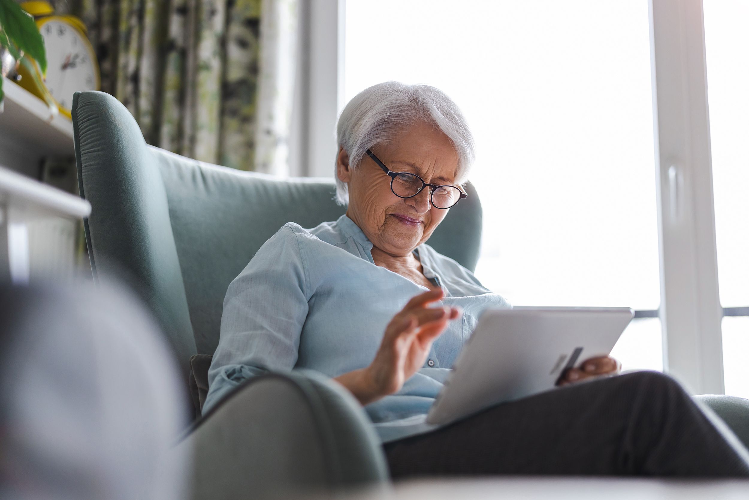 A woman uses a tablet in her living room. 