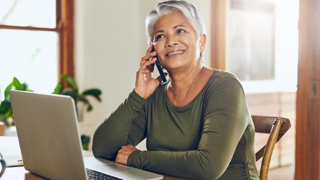 A woman uses her phone and her laptop.