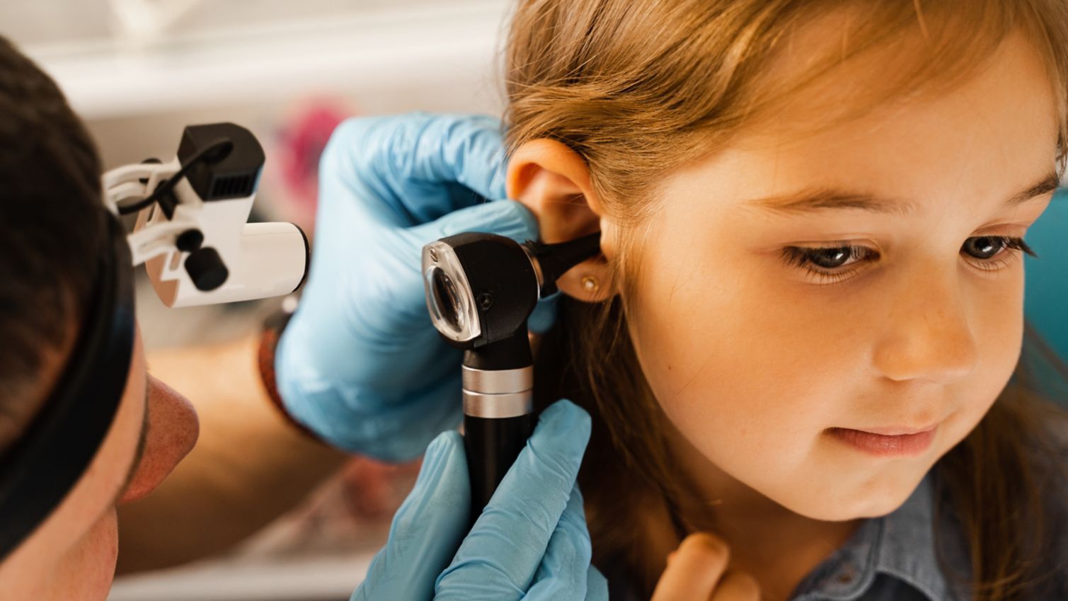 ENT doctor close-up examination of childs ear with otoscope.