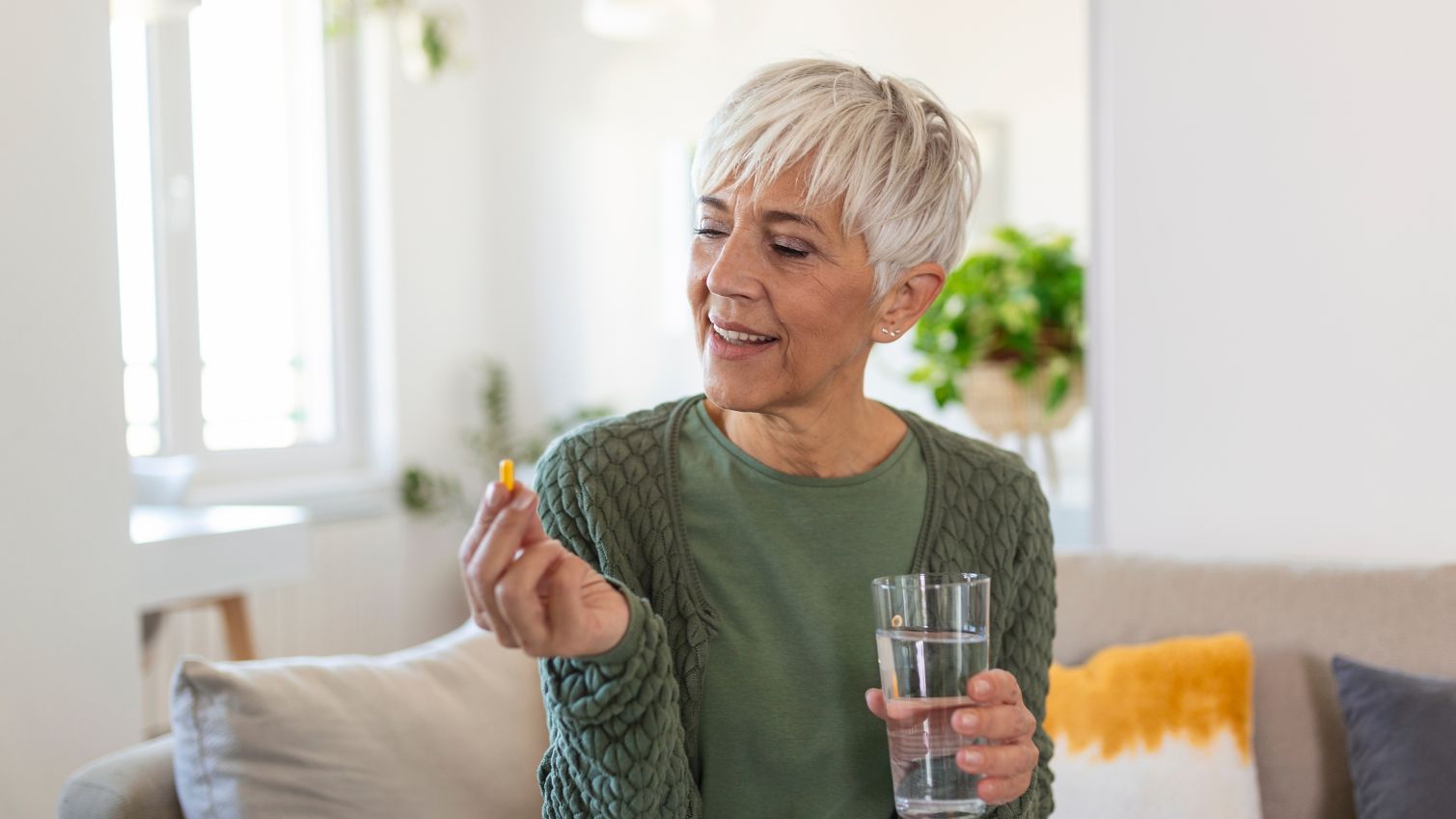 A woman looks at a pill she is about to take. 