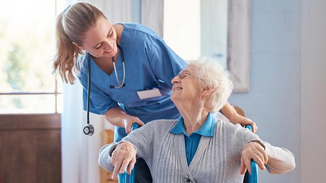 Patient smiles up at her care provider while being pushed in a wheelchair.