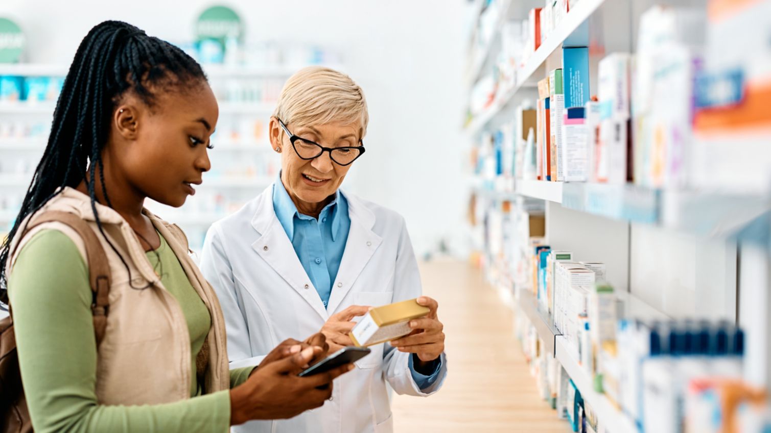Young woman gets advice from pharmacist while buying medicine in drugstore
