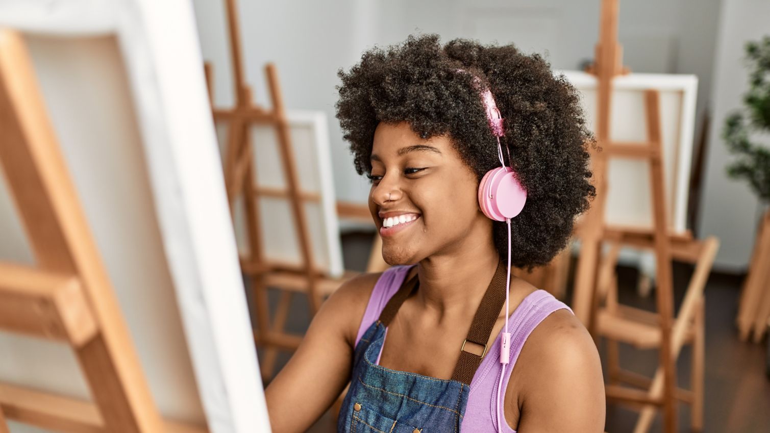 A woman paints while listening to music with headphones.